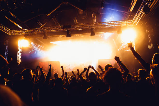 Colorful crowd of uncrecognized people of a big music festival or concert in a stage lights as a beautiful background