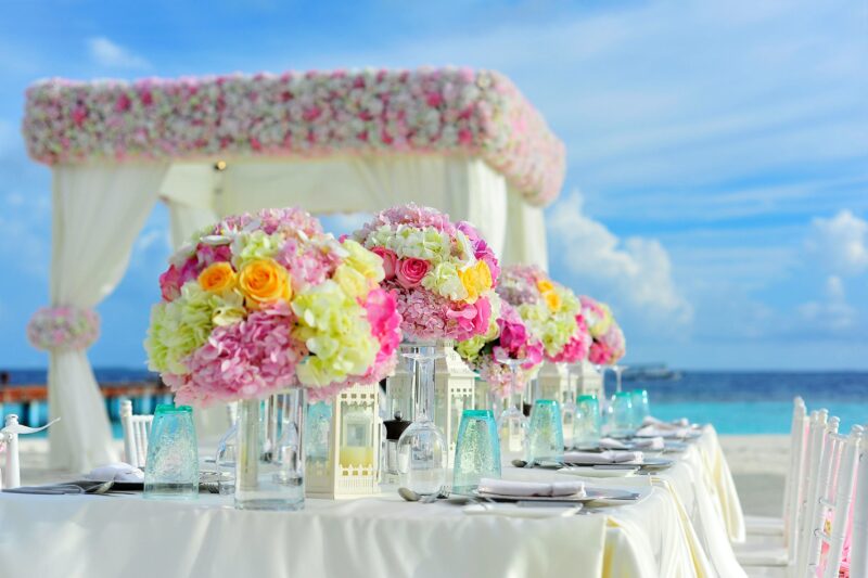 Flowers in vases on a table on the beach.